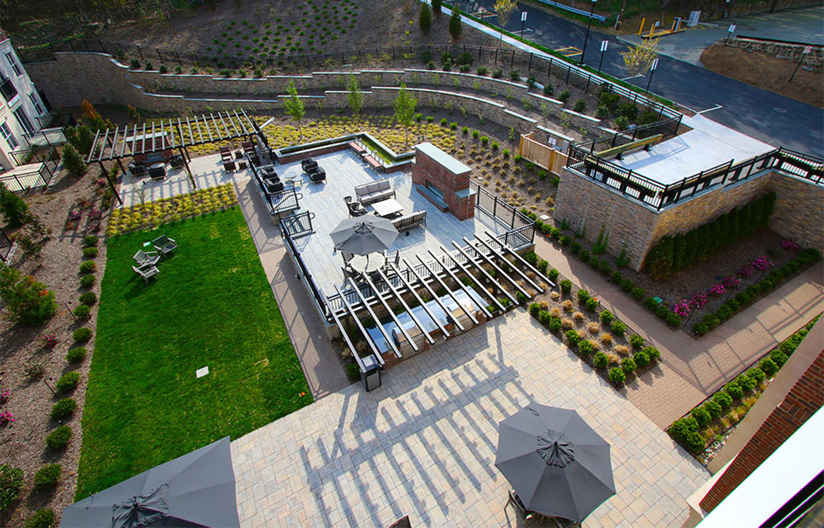 An aerial view of the 3,700 SF courtyard at the 30 Court residential development, showing pergolas, a fire pit, patios, lawns, landscape and various seating options.