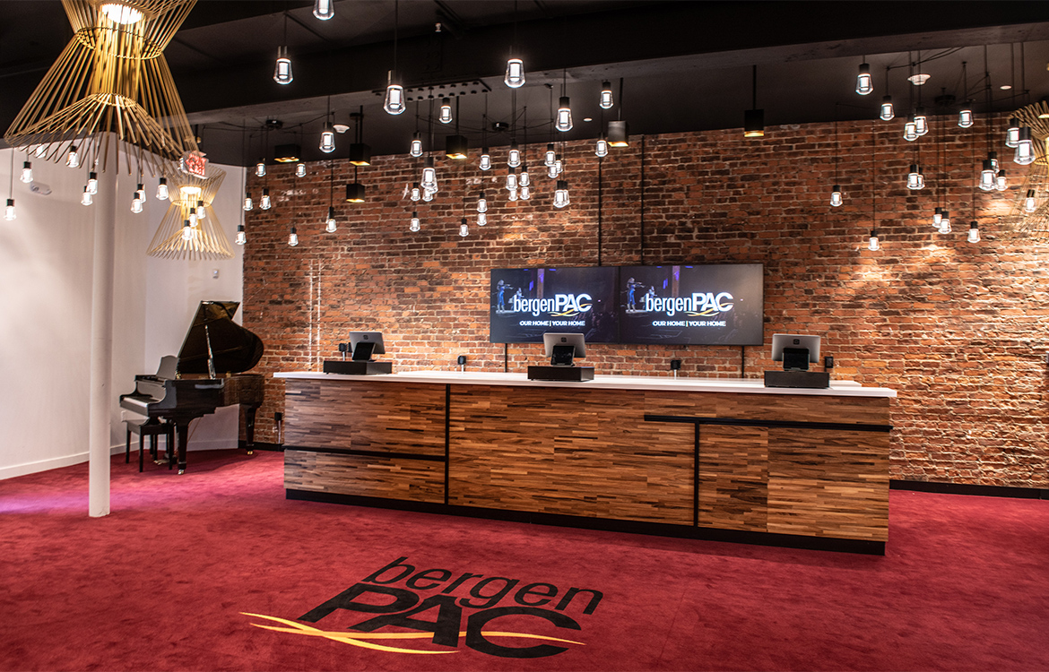 The new VIP area of bergenPAC, showing a bar and point-of-sale system in a space that includes eclectic light installations and exposed brick.