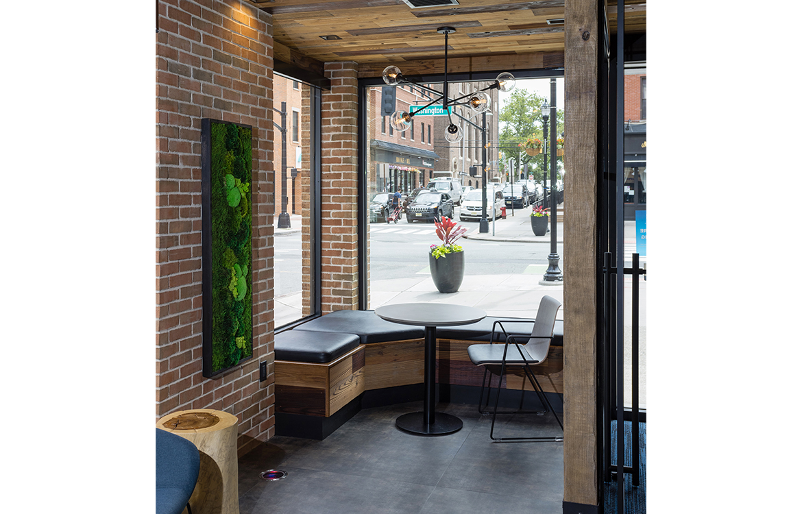 A small seating area inside the Blue Foundry Bank branch in Hoboken, NJ looks out onto the surrounding area. In the foreground is moss art, a consistent design feature across all bank branches.