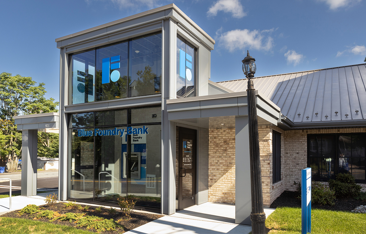The exterior of the renovated Blue Foundry Bank in Rutherford, NJ added a two-story vestibule, encased in glass, to the front of the existing building.