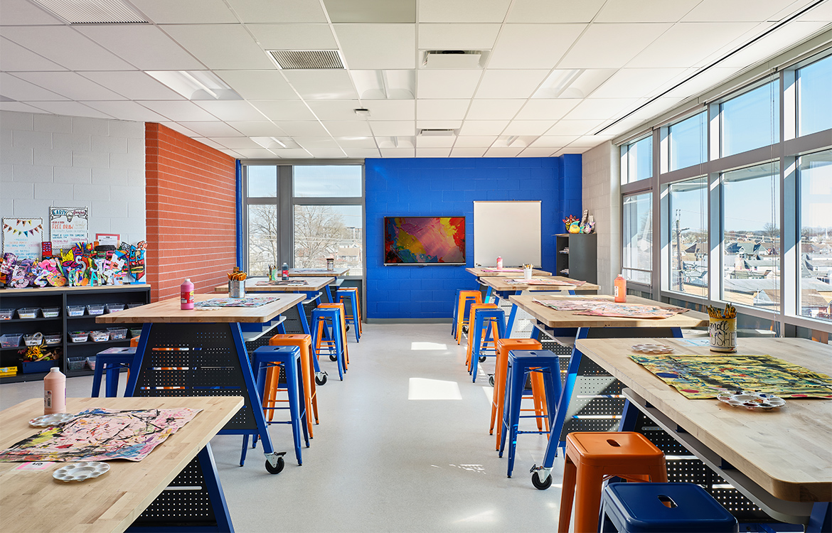 The art room at Carteret Junior High School is saturated with bright colors and student artwork, with moveable work benches and include supply storage.