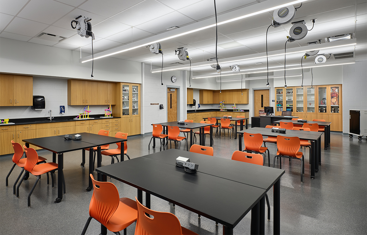 The science lab at Carteret Junior High School shows lab desks arranged in a small group format and electrical outlets hung from the ceiling to allow for easy transformation of the educational space.