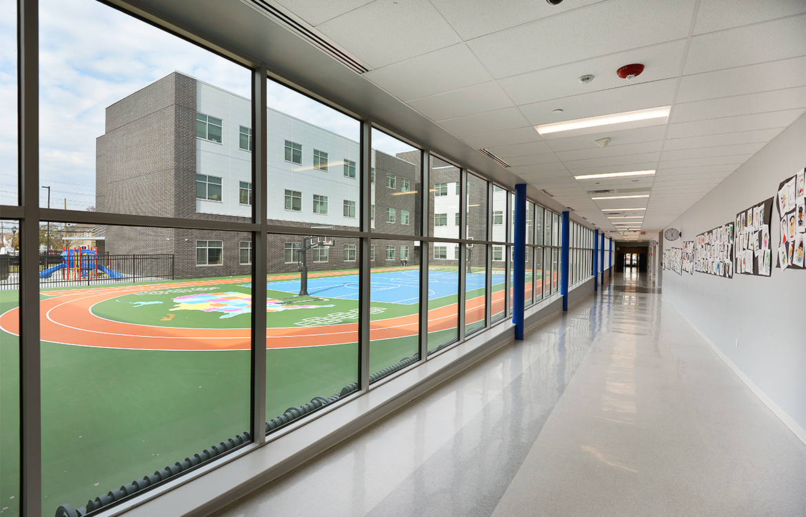 A hallway in the Blanquita B. Valenti Community School overlooks the playground. The walls include student artwork.