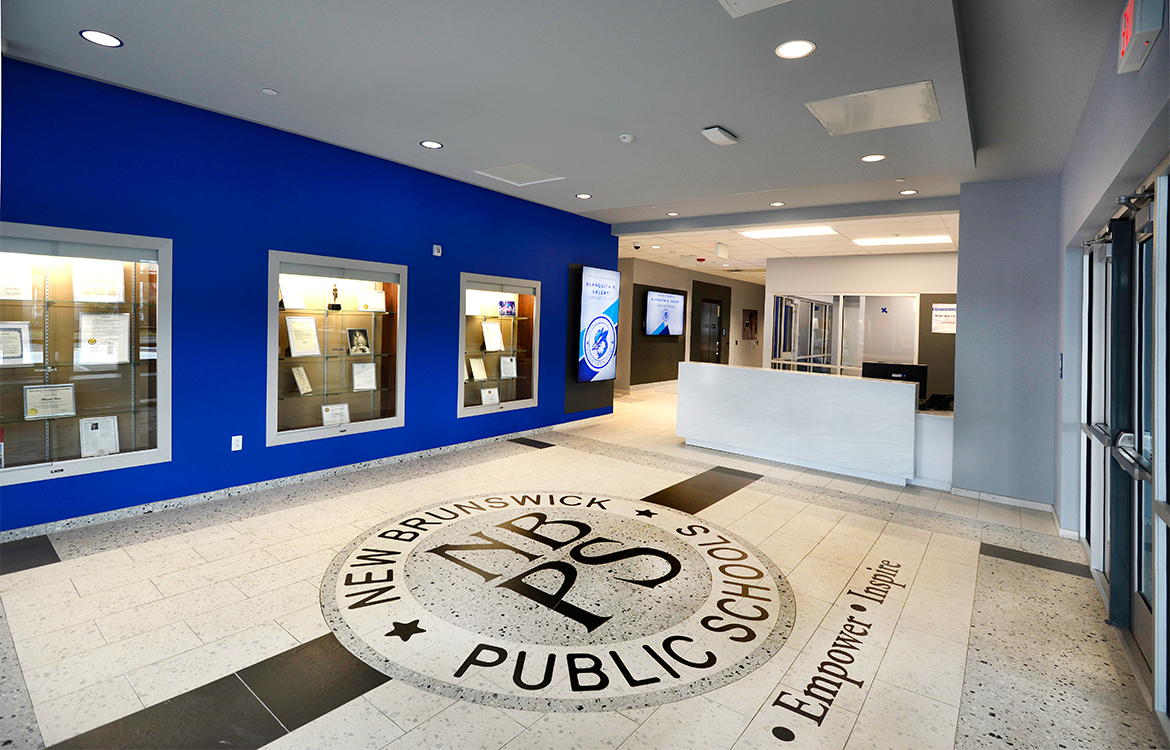 The main entrance lobby of the Blanquita B. Valenti Community School, including a security desk and display cabinets for noteworthy artifacts.