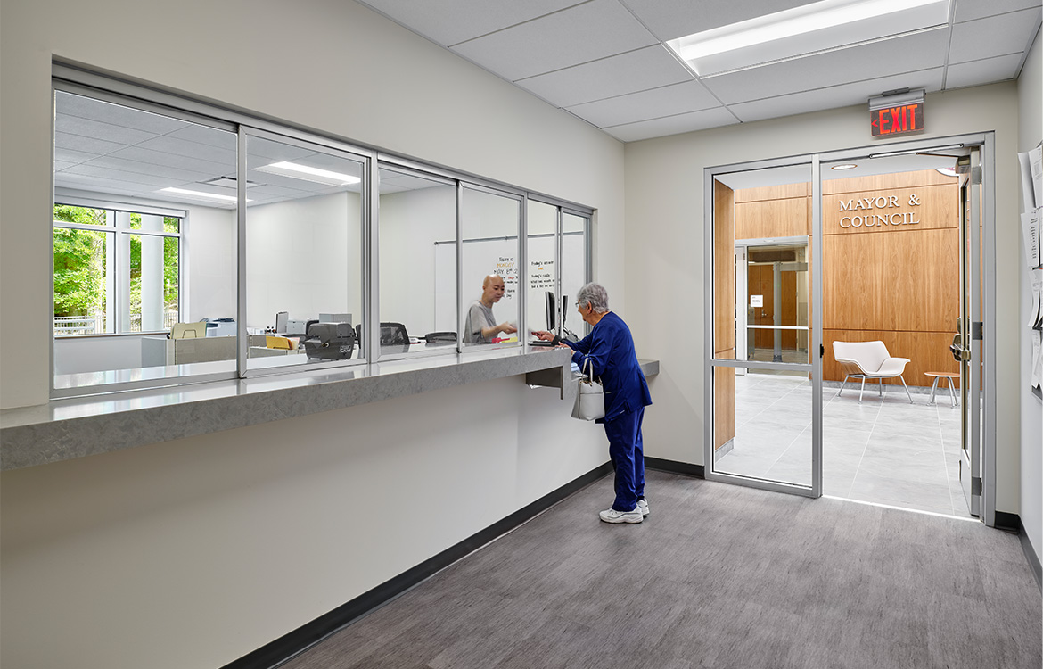 A patron is helped at the counter of the municipal offices located within the Ridgefield Municipal Complex. The image shows that the municipal offices are conveniently located directly off the main lobby.