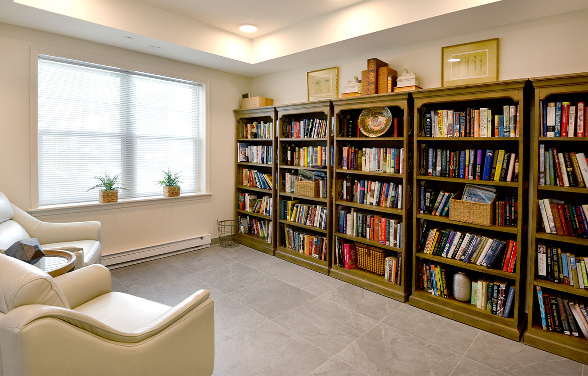 Two chairs in a small gathering area for residents, overlooking five bookcases filled with books.